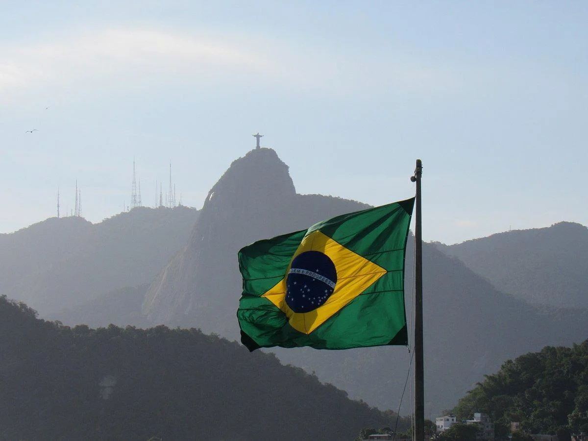 Bandeira do Brasil ao vento com o Cristo Redentor ao fundo