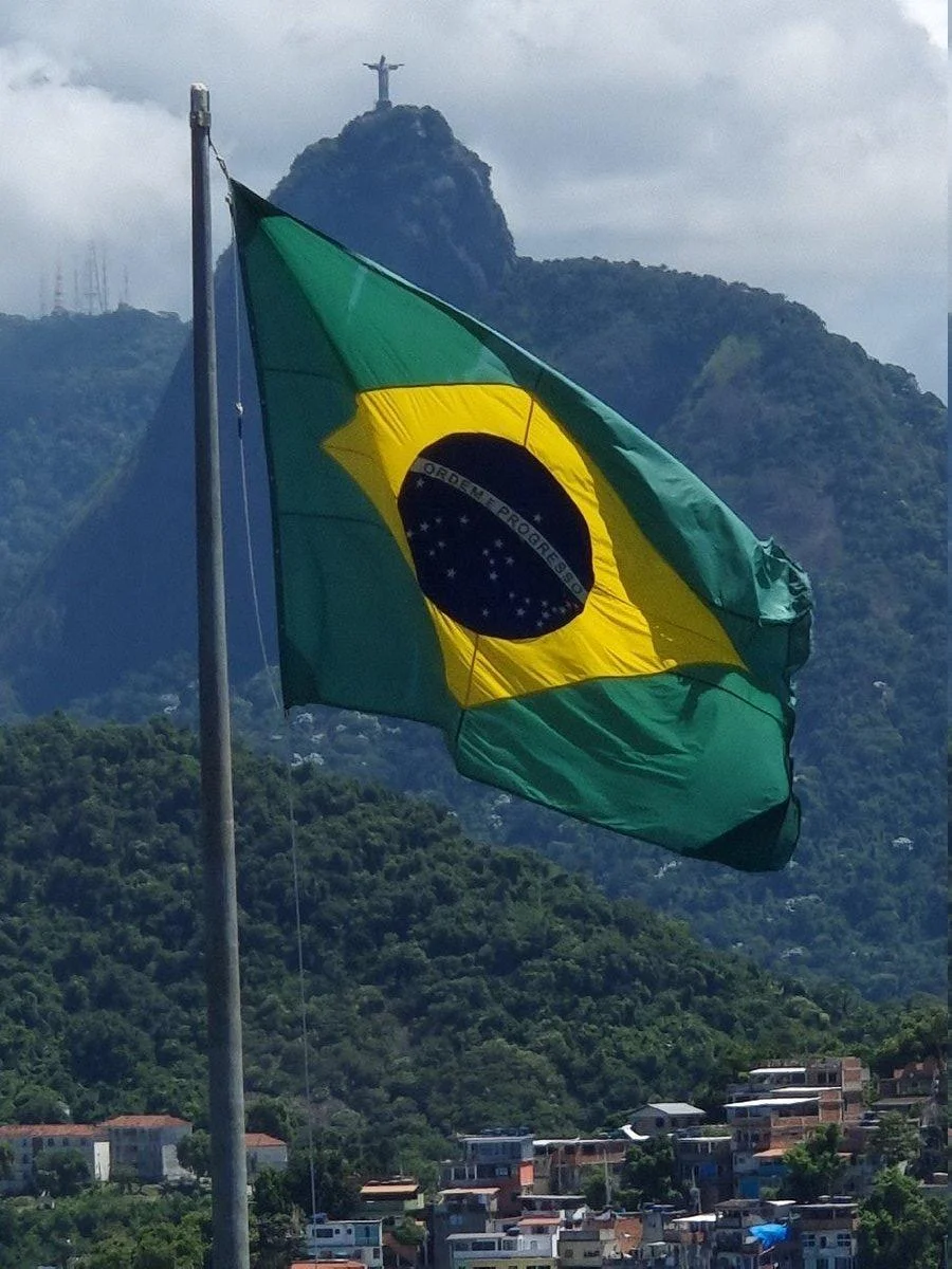 Bandeira do Brasil com Cristo Redentor e a comunidade ao redor — identidade carioca