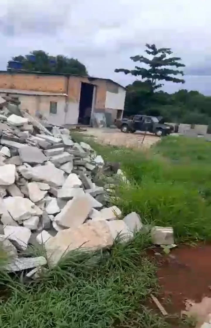 Pátio da usina com entulho, galpão de produção e área verde ao redor