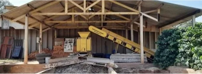 Galpão da usina com britador amarelo e esteira de triagem